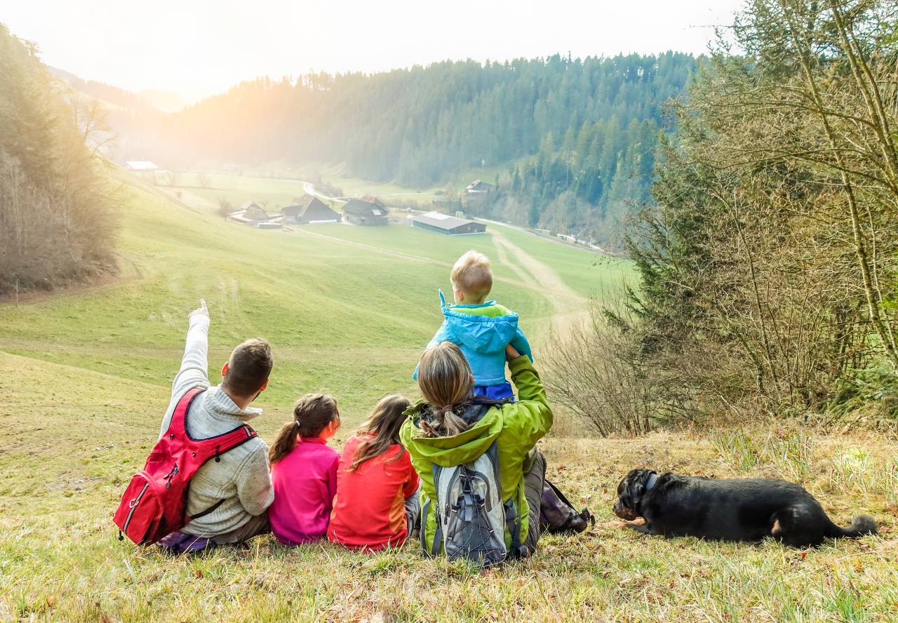Parents, children and dog overlooking meadow.