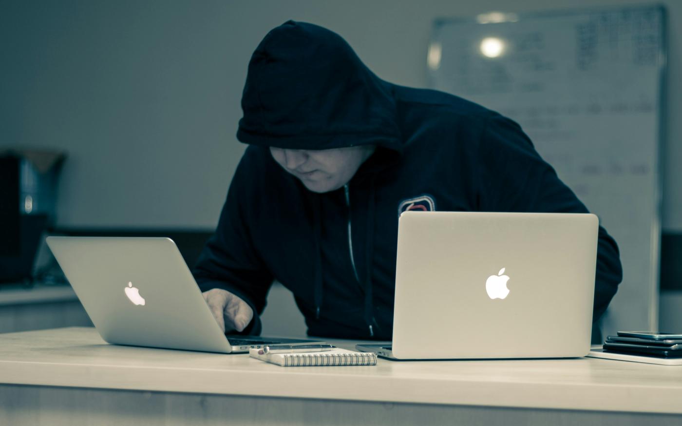 man in black hoodie using macbook by Azamat E courtesy of Unsplash.