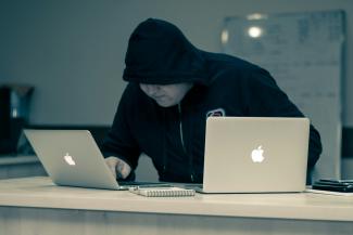 man in black hoodie using macbook by Azamat E courtesy of Unsplash.